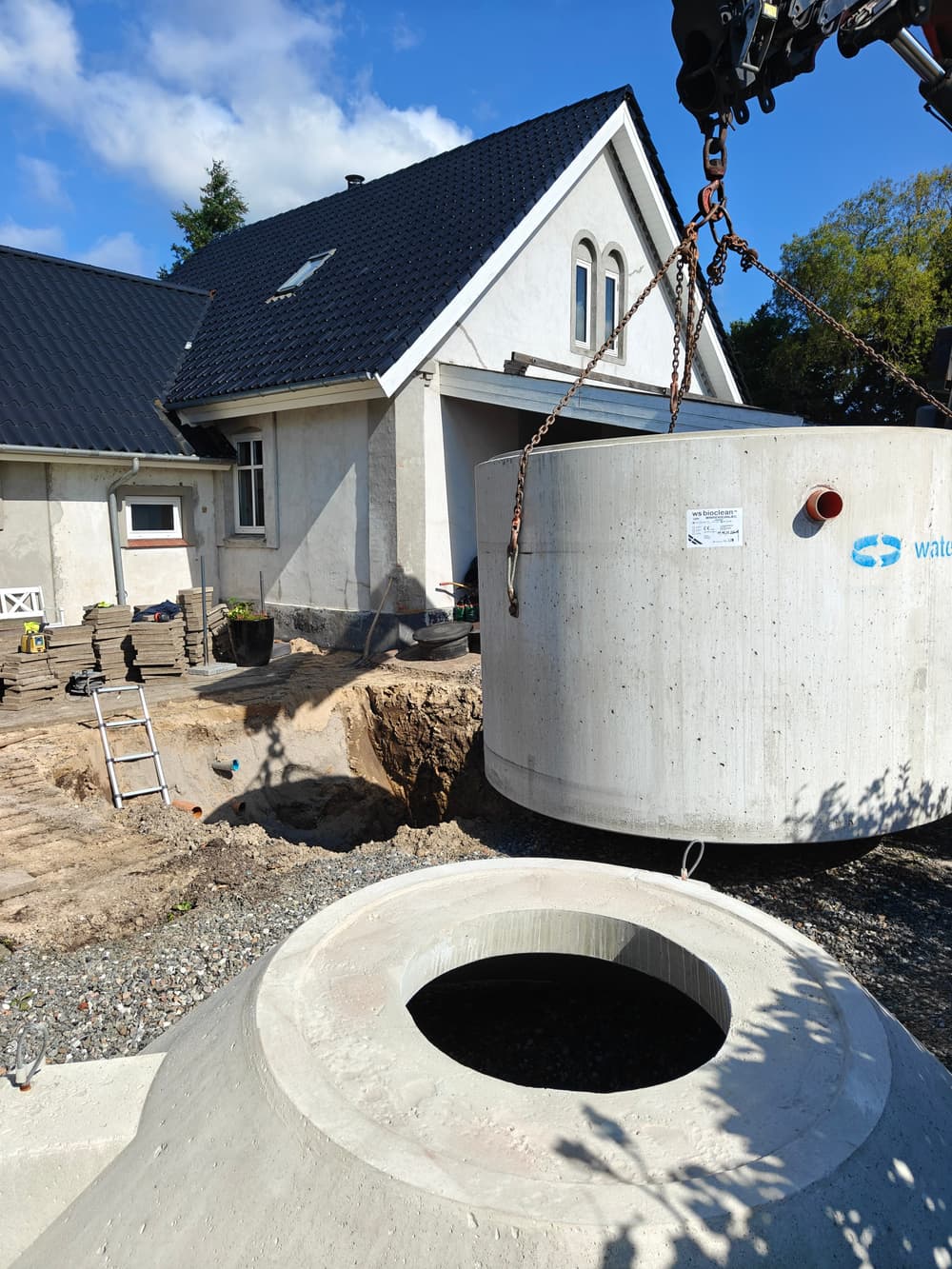 Betontanken til et minirenseanlæg løftes på plads med kran ved en privat bolig.